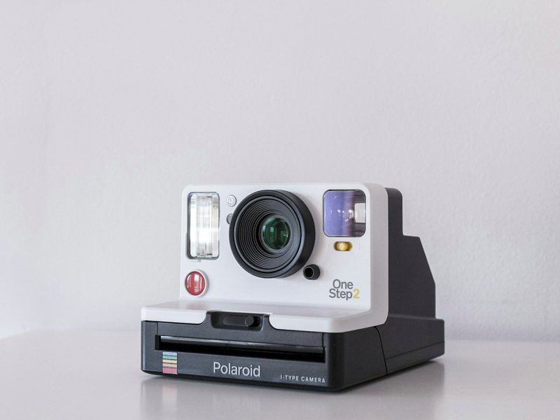 An instant camera on a plain ground, standing in for a retired photography accreditation