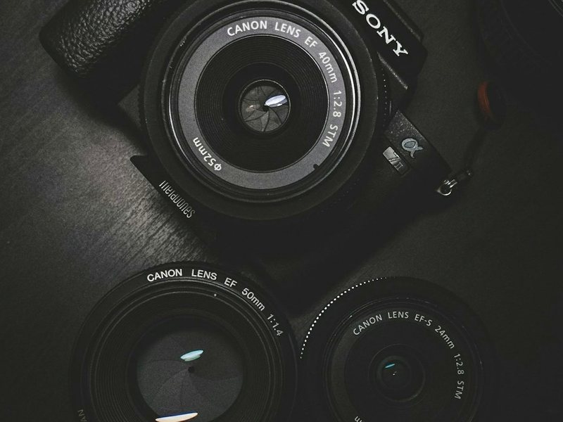 A digital camera body and lens photographed against a dark ground