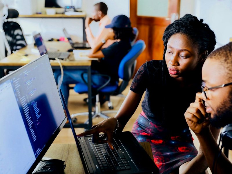 Two people working at laptops, reviewing an account setup